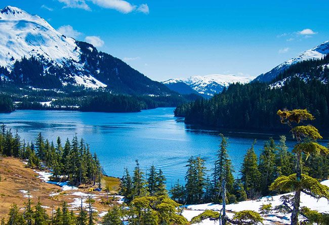 Snow-capped mountains above a calm Alaska inlet