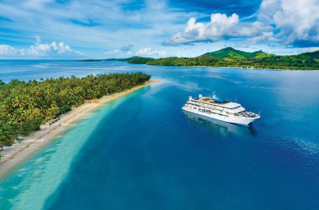 Small ship off a long white sandbar in the South Pacific