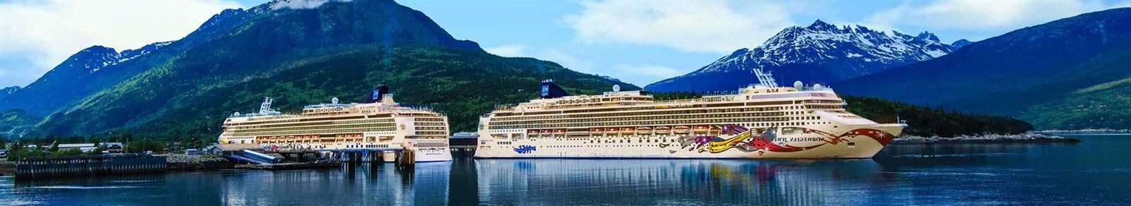 Cruise ship docked below forested mountains in Alaska