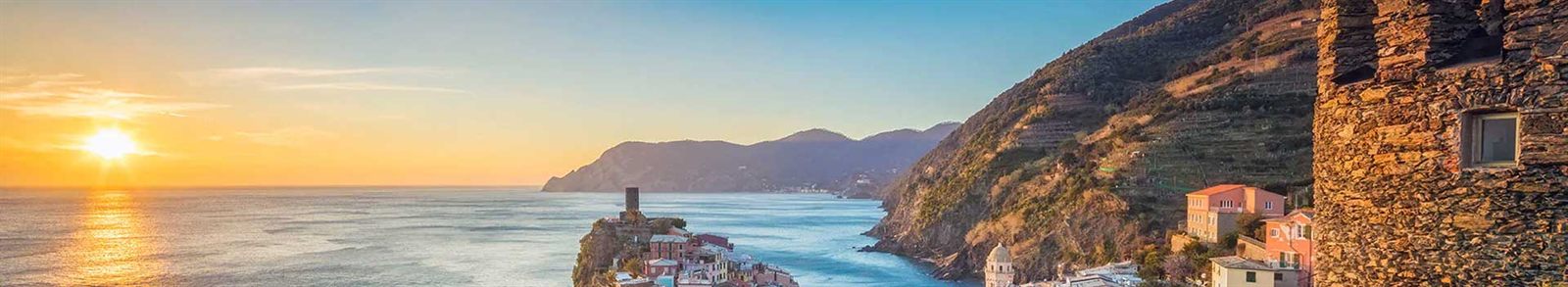 Rocky Mediterranean coastline and an old watchtower at sunset
