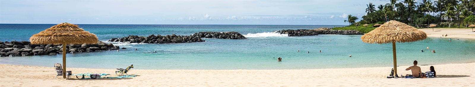 Calm turquoise water and a sandy beach behind a rock breakwater