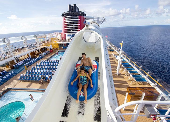 Parent and child riding a waterslide on a cruise ship deck