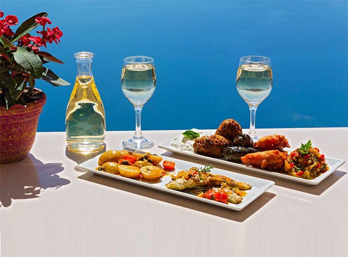 Glasses of white wine and small plates on a sunny table